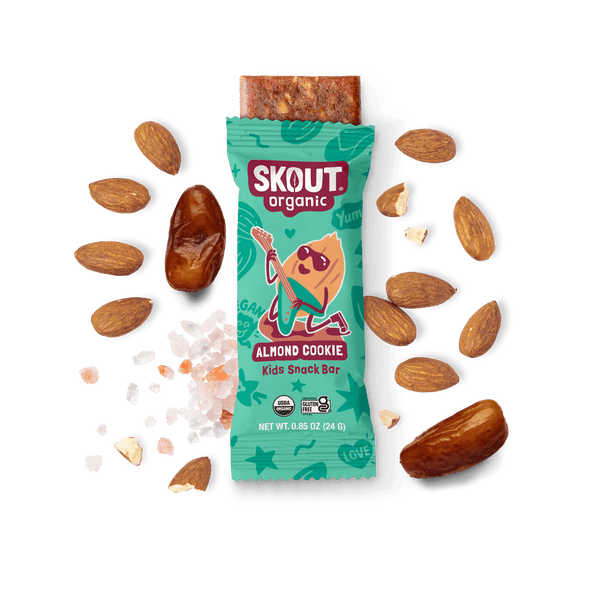Skout Organic Almond Cookie Kids Snack Bar in an open wrapper, surrounded by dates, almonds, and Himalayan pink salt.