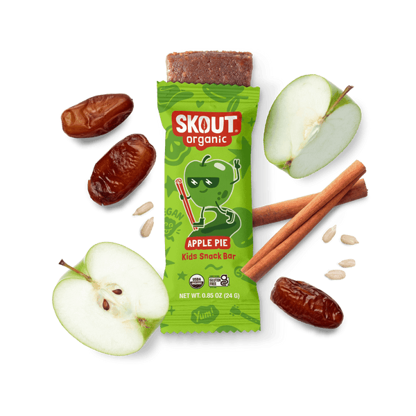 Skout Organic Apple Pie Kids Snack Bar in an open wrapper, surrounded by dates, apples, and cinnamon sticks.