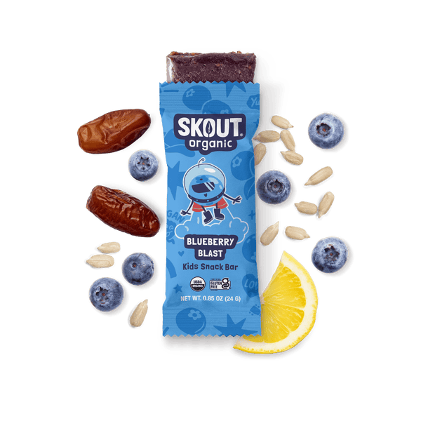 Skout Organic Blueberry Blast Kids Snack Bar in an open wrapper, surrounded by dates, blueberries, and a lemon wedge.
