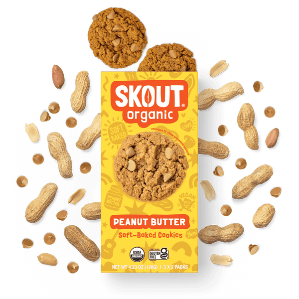 Skout Organic Peanut Butter Soft-Baked Cookies in an open box, surrounded by peanuts and peanut butter chips.